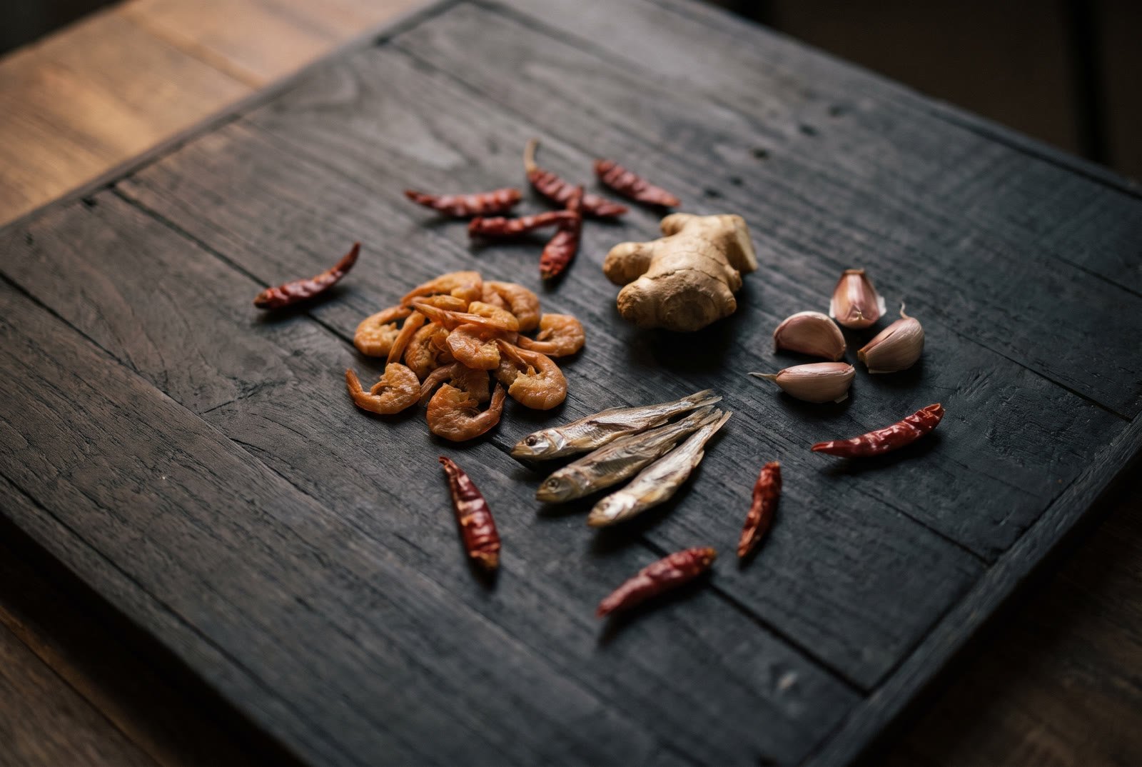Dried shrimp, dried fish, ginger, garlic and chillies on dark wood